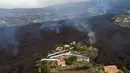 Lava dari letusan gunung Cumbre Vieja mengalir menghancurkan rumah-rumah di pulau La Palma di Canaries, Spanyol, Selasa (21/9/2021). Diketahui gunung berapi ini merupakan salah satu daerah vulkanik paling aktif di Canaries dan pernah mengalami letusan besar pada tahun 1971. (AP/Emilio Morenatti)