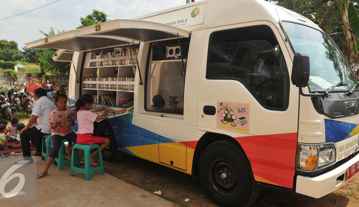 Sejumlah anak membaca buku di mobil perpustakaan keliling di halaman Rusun Cipinang Besar Selatan, Jakarta, Rabu (27/4). Pemprov DKI Jakarta melengkapi fasilitas rusun tersebut berupa perpustakaan dan taman bermain anak. (Liputan6.com/Gempur M Surya)