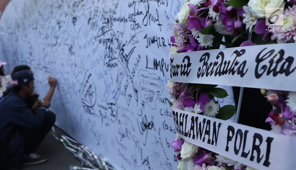 Karangan bunga diletakkan di sisi banner tulisan dukungan buat Polri pasca kerusuhan di Rutan cabang Salemba Mako Brimob saat acara Car Free Day di Kawasan Bundaran Hotel Indonesia, Jakarta, Minggu (13/5). (Liputan6.com/Helmi Fithriansyah)