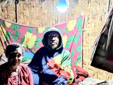 Warga duduk di bawah lampu listrik di Distrik Puldama, Kabupaten Yahukimo, Provinsi Papua. Jelang HUT ke-73 RI, untuk pertama kalinya warga Puldama menikmati lampu listrik di rumah mereka. (Liputan6.com/HO/Hadi M Juraid)