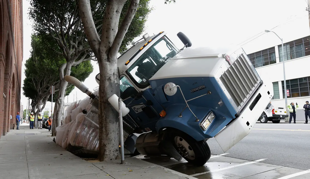 Sebuah truk terjebak di sebuah saluran pembuangan di San Francisco, AS, Jumat (5/5). Diduga karena muatan yang terlalu berat membuat bagian atas saluran pembuangan menjadi amblas. (AP Photo / Jeff Chiu)