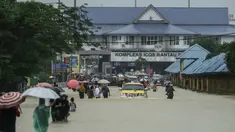 Warga menerobos banjir yang menggenangi jalanan di depan Kantor imigrasi dan bea cukai di Rantau Panjang, Selasa (3/1). Akibat hujan lebat yang turun terus menerus selama empat hari di Malaysia, 5000 warga terpaksa dievakuasi. (AFP PHOTO/STR/Malaysia OUT)