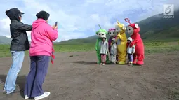 Wisawatawan mengambil gambar anaknya bersama karakter teletubbies di Bukit teletubbies kawasan Taman Nasional Bromo Tengger Semeru, Jawa Timur, Selasa (26/3). Kegiatan yang berlangsung sejak sekitar 1,5 bulan lalu ini dilakukan warga asli Tengger dengan seizin pihak TNBTS. (merdeka.com/Arie Basuki)