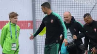 Pemain Portugal, Cristiano Ronaldo (dua kiri) menyalami anak bola saat sesi latihan perdana jelang Piala Dunia 2018 di base camp mereka di Kratovo, pinggiran Moskow, Rusia, Minggu (10/6). (Francisco LEONG/AFP)