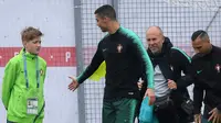 Pemain Portugal, Cristiano Ronaldo (dua kiri) menyalami anak bola saat sesi latihan perdana jelang Piala Dunia 2018 di base camp mereka di Kratovo, pinggiran Moskow, Rusia, Minggu (10/6). (Francisco LEONG/AFP)