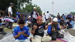 Para buruh berdoa bersama usai melaksanakan salat Jumat di kawasan Monas, Jakarta, Jum'at (1/5/2015). Lebih dari 100.000 buruh ikut dalam aksi May Day.(Liputan6.com/Andrian M Tunay) 