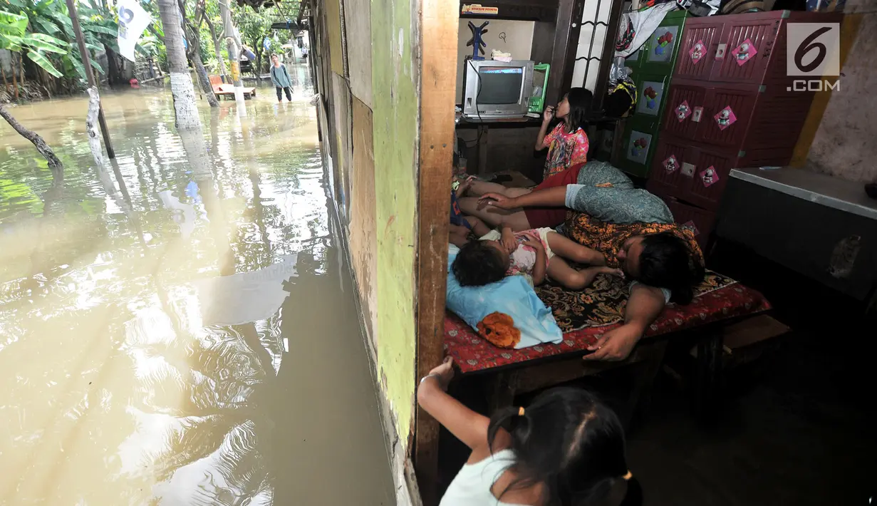 Warga beristirahat di dalam rumah saat banjir menggenangi kawasan Rawa Terate, Cakung Jakarta, Rabu (30/1). Ratusan rumah di RT 016/004 dan RT 010/005 Kelurahan Rawa Terate, terendam banjir sejak dini hari. (merdeka.com/Iqbal S. Nugroho)