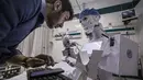Mahmoud El Komy, seorang insinyur mekatronika, memeriksa kode di layar prototipe robot CIRA-03 kendali jarak jauh yang didanai sendiri untuk membantu dokter dalam menjalankan tes pada pasien yang dicurigai COVID-19 di rumah sakit swasta di kota Tanta, Mesir pada 20 Maret 2021. (Khaled DESOUKI/AFP)