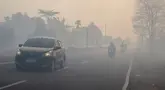 Para pengendara bermotor menyalakan lampu depan kendaraan saat melintasi jalan yang diselimuti kabut asap di Kota Palangka Raya, Kalimantan Tengah, Kamis,  20 Agustus 2026. (AFP/ Reina)