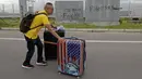 Seorang penumpang membawa koper berjalan kaki ke bandara ketika pemrotes pro-demokrasi memblokir jalan di luar bandara di Hong Kong (1/9/2019). Akibat pemblokiran jalan dan layanan kereta api para calon penumpang pesawat terpaksa berjalan kaki menuju bandara. (AP Photo/Kin Cheung)