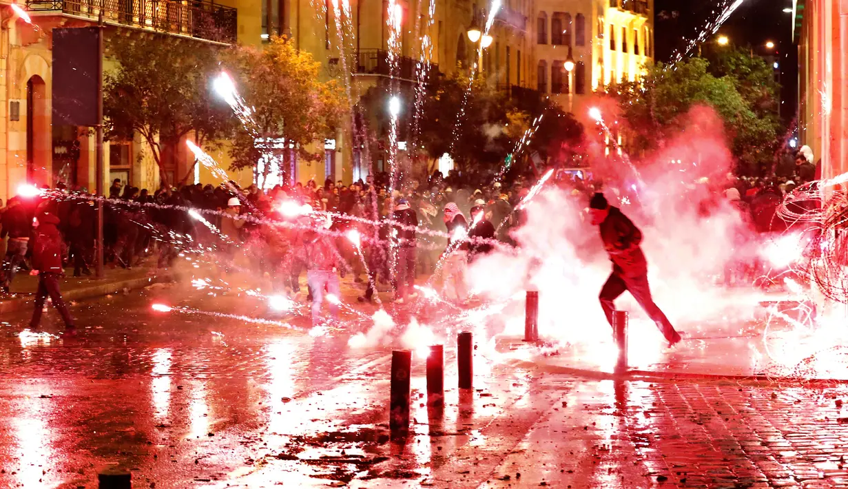 Amarah Lebanon Tolak Kabinet Baru: Demonstran antipemerintah melemparkan petasan ke arah polisi antihuru-hara saat demonstrasi menentang pemerintahan baru di dekat Parliament Square, Beirut, Rabu (22/1/2020). (AP/Hussein Malla)