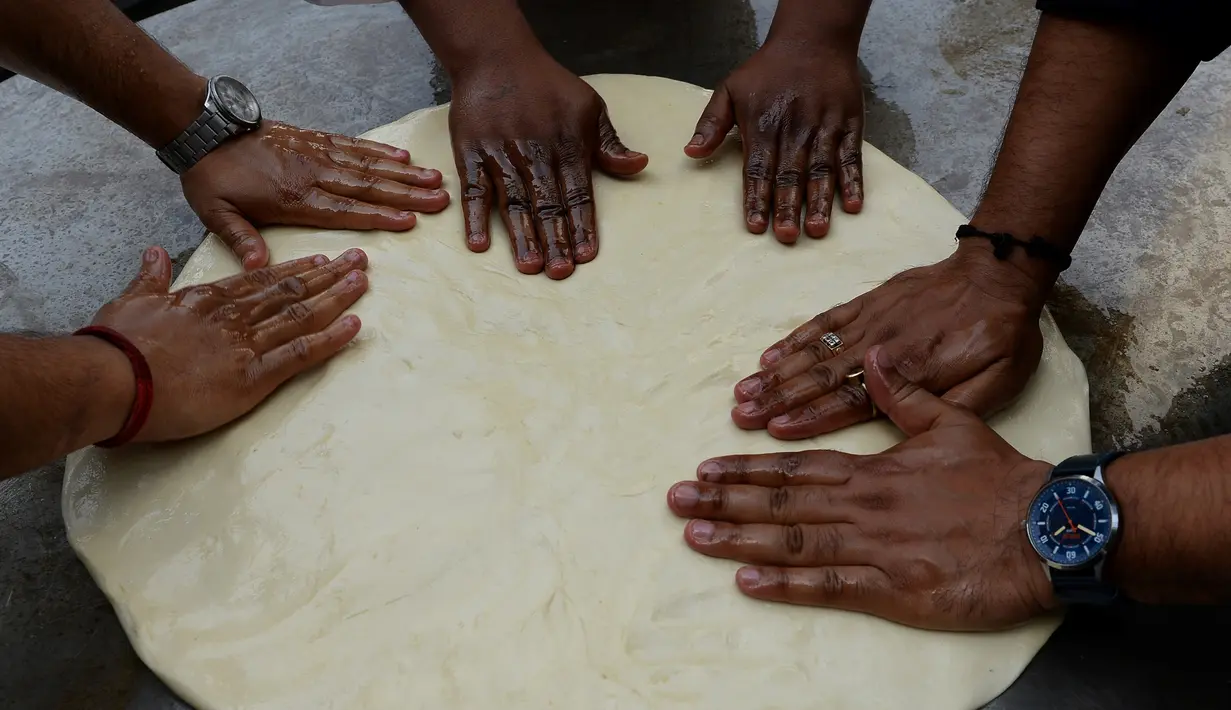 Koki India menyiapkan adonan untuk membuat roti goreng yang dikenal dengan sebutan Bhatura, India, New Delhi, Kamis (6/4). Penyelenggara berharap Bhatura buatan mereka bisa memecahkan rekor Bhatura  terbesar di India. (AFP PHOTO / SAJJAD HUSSAIN)