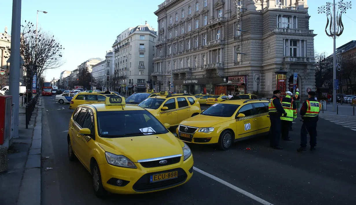 Petugas keamanan berjaga selama pemblokiran yang dilakukan Sejumlah Sopir taksi yang menolak layanan aplikasi  Uber di Budapest, Hongaria, (18/1). Tuntutan mereke berisi tentang resiko adanya aplikasi Uber terhadap pekerjaan mereka.  (AFP / Ferenc ISZA)