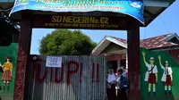 MUrid SD Negeri 62 Kota Bengkulu terpaksa masuk ke sekolah dengan pintu yang hanya dibuka beberapa jengkal saja. (Liputan6.com/Yuliardi Hardjo)