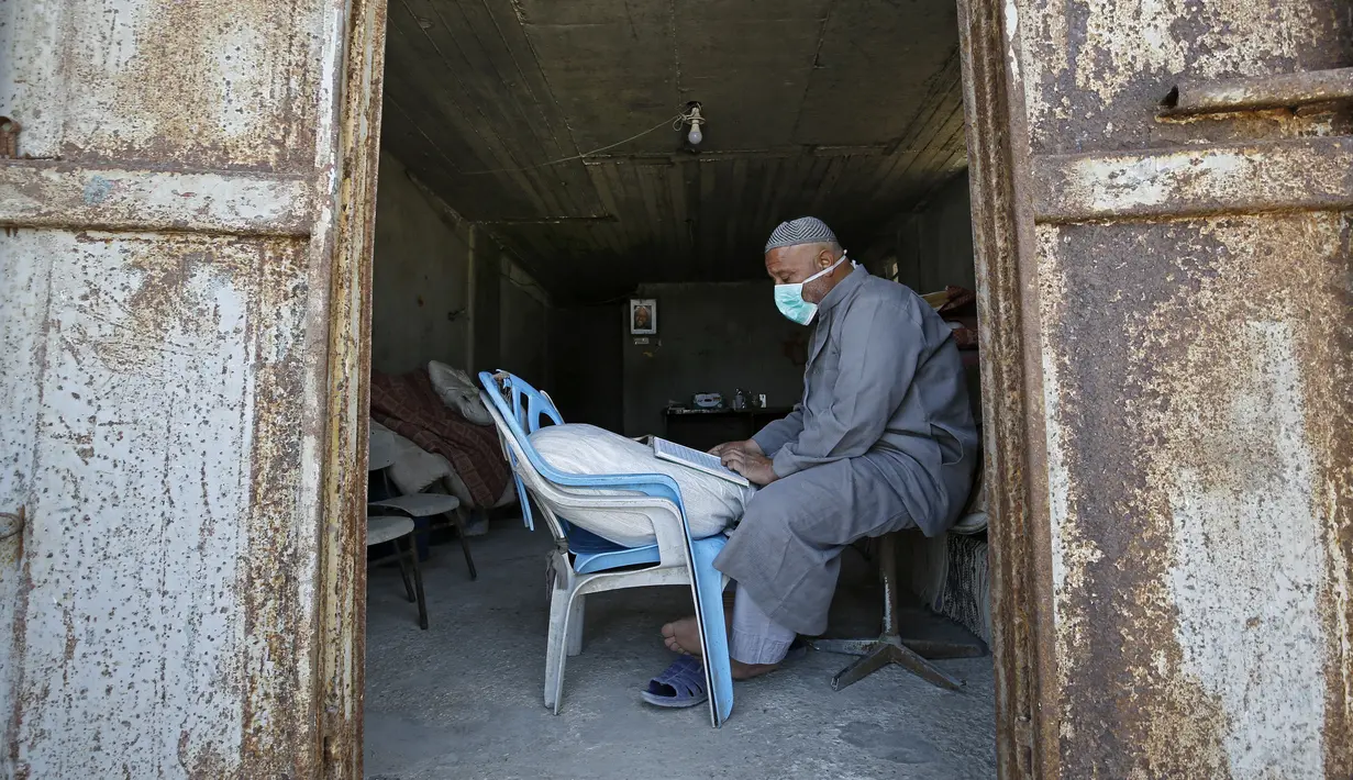 Seorang tukang roti membaca Al-Quran selama bulan suci Ramadan di Kota Gaza, Palestina, Jumat (1/5/2020). (MOHAMMED ABED/AFP)