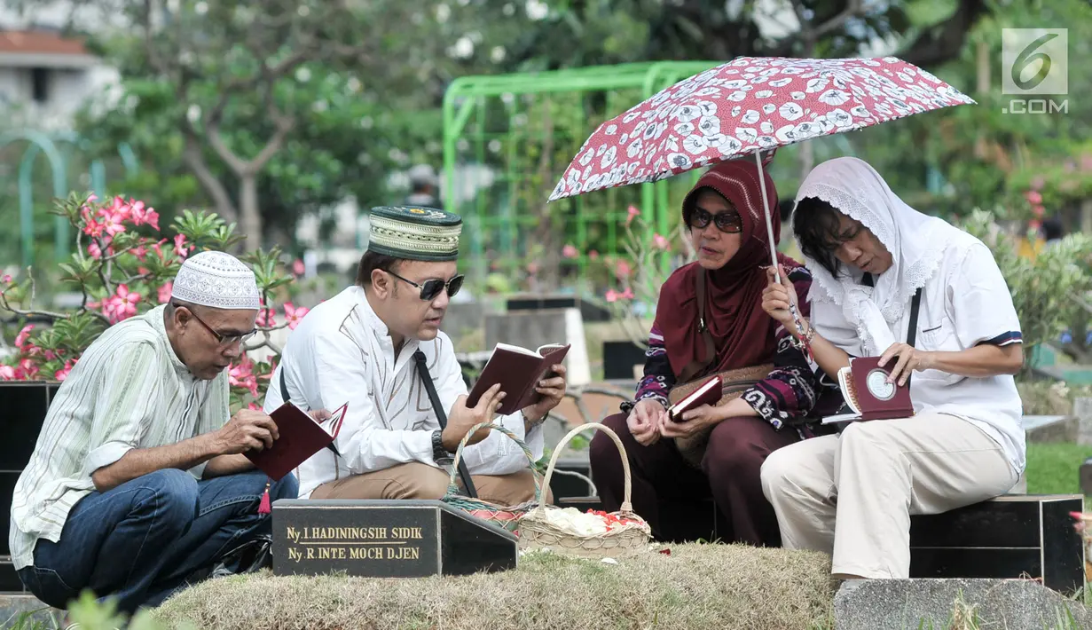 Umat muslim berdoa di dekat pusara keluarganya saat ziarah di TPU Karet Bivak, Jakarta, Minggu (25/6). Hari pertama Lebaran, sejumlah warga memadati TPU untuk melangsungkan tradisi ziarah usai salat Idul Fitri. (Liputan6.com/Yoppy Renato)