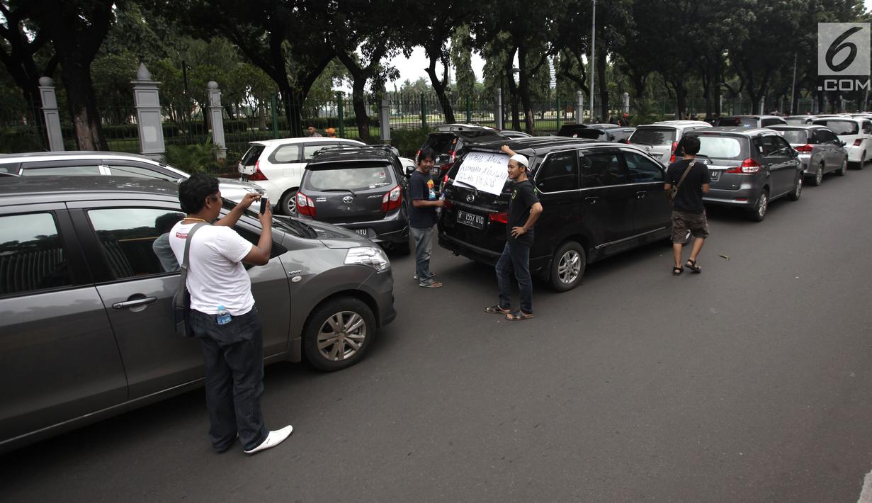 Sejumlah sopir taksi online berpose saat demo di Jalan Medan Merdeka Barat, Jakarta, Rabu (14/2). Para pengemudi meminta Menteri Perhubungan Budi Karya untuk menghapus Permenhub Nomor 108 Tahun 2017. (Liputan6.com/Arya Manggala)