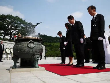 Presiden Korea Selatan Yoon Suk Yeol (tengah) dan istrinya Kim Keon-hee (tengah kiri) memberikan penghormatan dalam upacara peringatan Memorial Day ke-68 di Pemakaman Nasional, Seoul, Korea Selatan, Selasa (6/6/2023). (KIM HONG-JI/POOL/AFP)