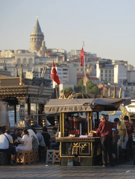 Orang-orang duduk di distrik Eminonu dengan latar belakang Menara Galata, di Istanbul, Selasa (27/7/2021). Turki telah mencatat lebih dari 15.000 kasus virus corona baru, karena jumlah infeksi yang terus meningkat. (AP Photo/Mucahid Yapici)