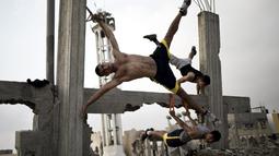 Anggota Bar Palestine, berlatih Street workout di bekas reruntuhan bangunan di kota Gaza, Palestina. Street workout adalah latihan yang dilakukan di luar ruang dengan memanfaatkan fasilitas yg ada. (AFP Photo/Mohammed Abed)