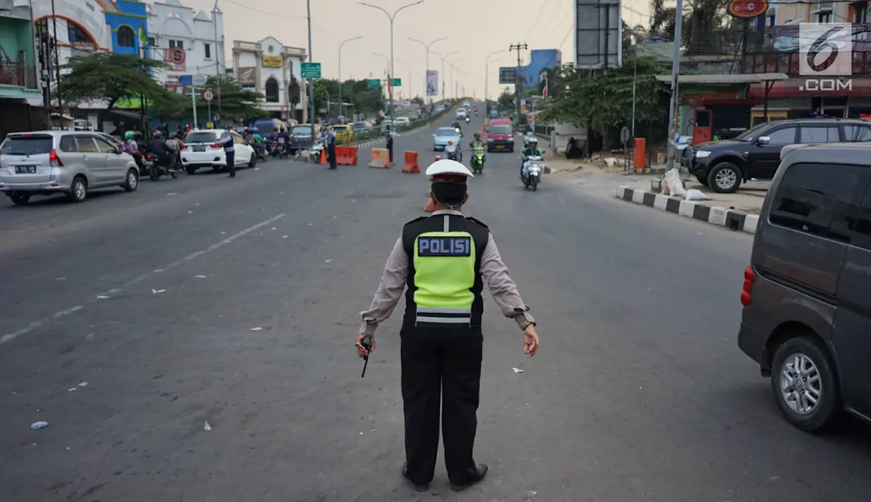 Polisi berjaga di lampu merah persimpangan Ramanda, Depok, Jawa Barat, Rabu (14/8/2019). Pemutaran lagu Wali Kota Depok Mohammad Idris di lampu merah tersebut sebagai bagian dari konsep Joyful Traffic Management (Jotram). (Liputan6.com/Immanuel Antonius)