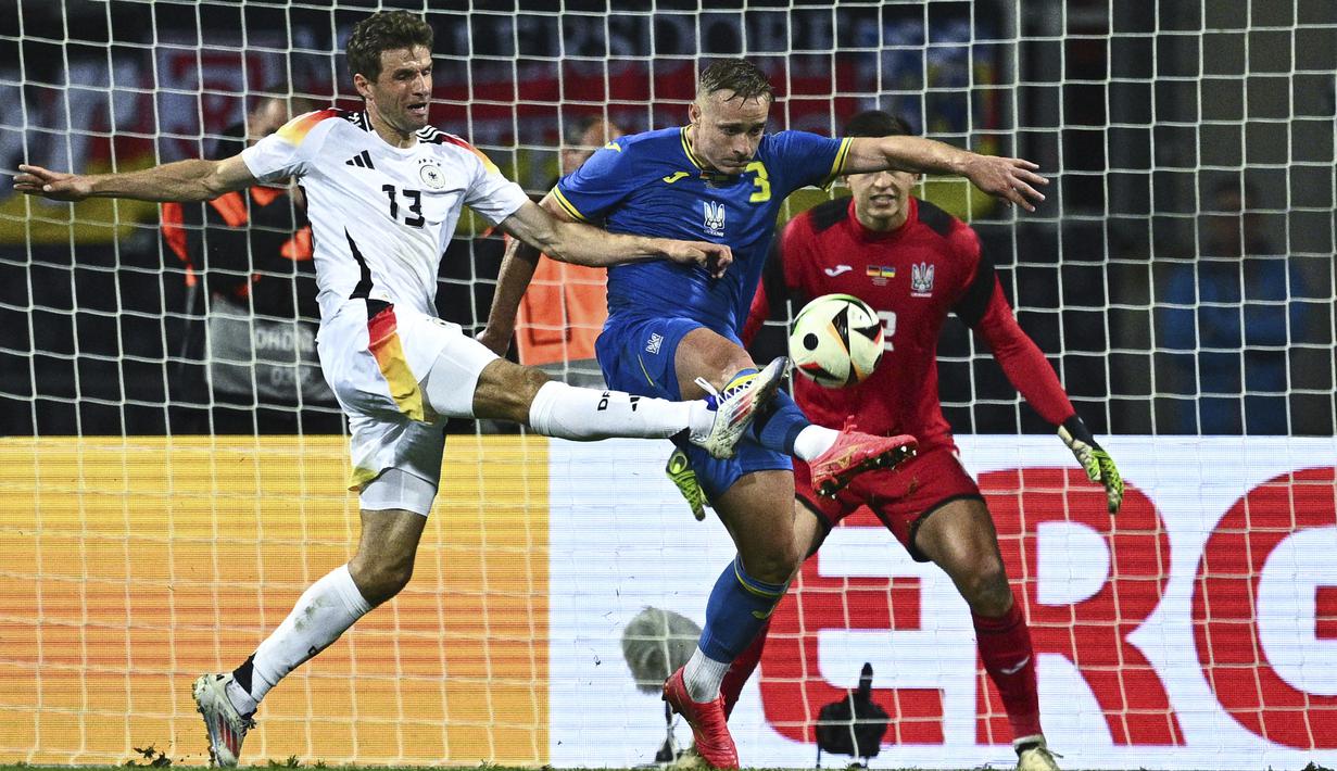 Penyerang Jerman, Thomas Muller berebut bola melawan bek Ukraina Oleksandr Swatok (tengah) dan kiper Anatolij Trubin dalam laga uji coba jelang Piala Eropa 2024 di Stadion Max Morlock, Nurenberg, Selasa (4/6/2024). (Tom Weller/dpa via AP)