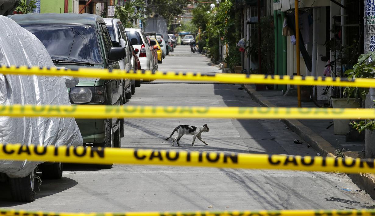 Seekor kucing melintasi jalan kosong di desa yang dikunci di Manila  (11/3/2021). Ibukota Filipina menempatkan dua desa, dua hotel diisolasi dan polisi telah memperingatkan agar tidak berciuman dan "bermesraan kasih sayang di depan publik" setelah lonjakan infeksi Covid-19. (AP Photo/Aaron Favila)