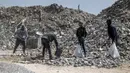 Para pekerja memecahkan puing-puing saat mereka mendaur ulang bahan bangunan yang diselamatkan dari bangunan yang hancur selama konflik Mei 2021 antara Hamas dan Israel di area pengumpulan puing-puing di Shujaiya, pinggiran timur Kota Gaza, Sabtu (5/6/2021). (MAHMUD HAMS/AFP)