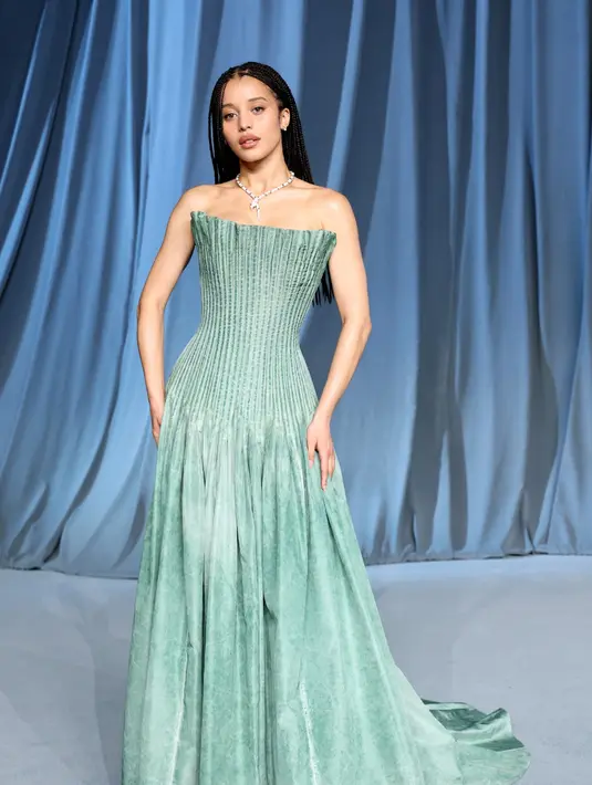 Sementara itu, Chase Infiniti memancarkan pesona feminin dalam gaun bustier sutra taffeta berwarna hijau lembut yang dihiasi lipit-lipit halus. Potongan dan warna gaun ini memberikan kesan segar sekaligus elegan di antara nuansa malam yang glamor. [Dok/Louis Vuitton].