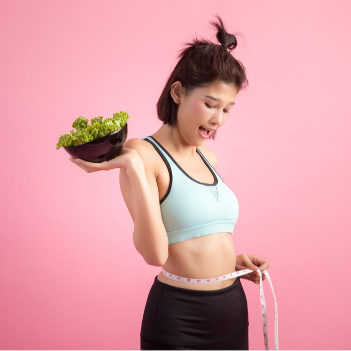 Wanita yang Mengukur Badannya dan Membawa Makanan Dietnya