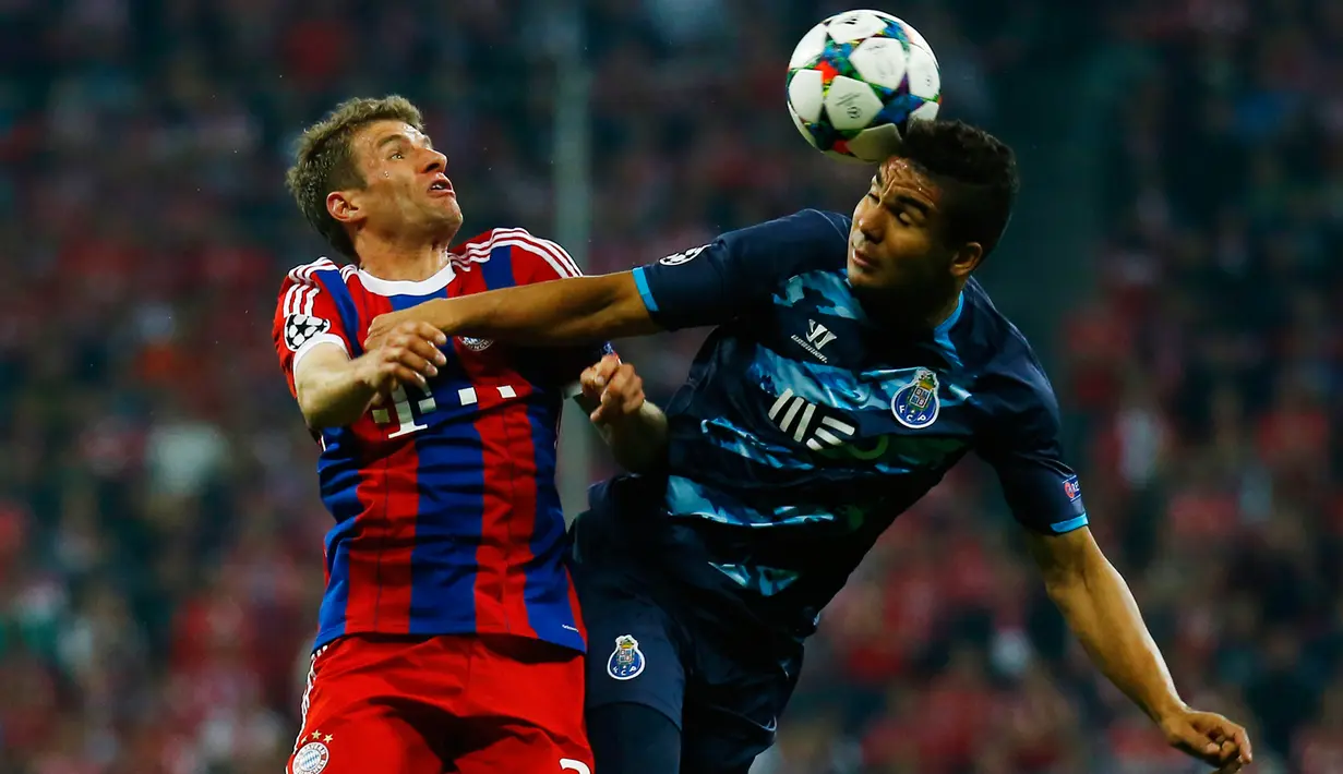 Penyerang Bayern Muenchen, Thomas Muller (kiri) berebut bola udara dengan pemain Porto  Casemiro di leg kedua perempat final Liga Champions di Allianz Arena, German, Rabu (22/4/2015). Bayern Muenchen menang 6-1 atas Porto. (Reuters/Kai Pfaffenbach)