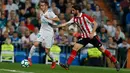 Pemain Real Madrid, Lucas Vazquez berebut bola dengan pemain Athletic Bilbao, Raul Garcia pada pekan ke-33 La Liga di Santiago Bernabeu, Rabu (18/4). Real Madrid kembali meraih hasil minor usai bermain imbang 1-1 lawan Atletico Bilbao. (AP/Francisco Seco)