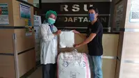 Perwakilan PSSI Pers, Muhammad Ridwan (kanan), memberikan donasi berupa Alat Pelindung Diri (APD) untuk kebutuhan tenaga medis di RSUD Tangerang Selatan yang tengah berjuang menghadapi pandemi virus corona. (Istimewa)