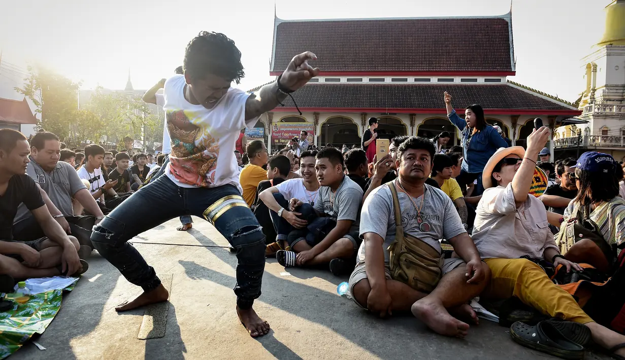 Seorang pria pria kesurupan saat mengikuti festival tato suci di Biara Wat Bang Phra, Nakhon Pathom, Thailand (3/3). Dalam festival ini kesurupan merupakan tanda bahwa proses mengisi kekuatan tato sedang berlangsung. (AFP Photo/Lillian Suwanrumpha)