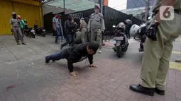 Petugas gabungan memberikan hukuman push up kepada warga yang tidak memakai masker saat razia Pembatasan Sosial Berskala Besar (PSBB) di Kawasan Jalan Fatmawati, Jakarta, Selasa (28/4/2020). Penertiban terkait pelaksanaan PSBB Jakarta dan memutus rantai penyebaran COVID 19. (merdeka.com/Imam Buhori)