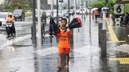 Seorang anak menawarkan jasa ojek payung di tengah hujan yang turun di kawasan Bundaran HI, Jakarta, Senin (3/2/2020). Hujan deras yang mengguyur sejumlah wilayah di DKI Jakarta dimanfaatkan para pengojek payung untuk mencari penghasilan tambahan. (Liputan6.com/Angga Yuniar)