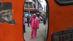 Fashionista Kenya, James Mwangi Maina bermain ponsel sambil memamerkan setelan jasnya yang senada dengan pakaian dan aksesorisnya, termasuk masker di Nairobi, 5 Agustus 2020. Mwangi mengklaim dirinya memiliki penampilan terbaik dan paling stylish di Afrika. (Simon MAINA/AFP)