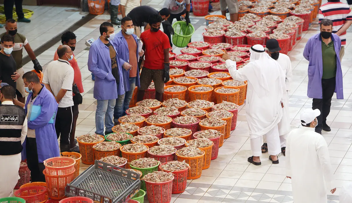 Orang-orang berbelanja selama pelelangan di pasar ikan di Kuwait City (8/8/2021). Pelelangan dibuka kembali di negara itu setelah enam bulan ditutup di tengah pandemi virus corona. (AFP/ Yasser Al-Zayyat)