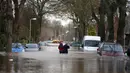 Warga melintasi banjir yang merendam pemukiman Warwick Road Carlisle, Inggris, Minggu (6/12). Puluhan ribu rumah tidak punya listrik karena Badai Desmond yang menyebabkan banjir di Inggris utara dan sebagian Skotlandia. (REUTERS/Phil Noble)