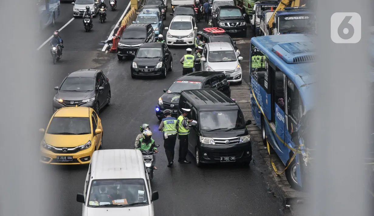 Petugas kepolisian menilang pengendara mobil yang melanggar aturan ganjil genap di Jalan MT Haryono, Jakarta, Kamis (28/10/2021). Para pelanggar sistem ganjil genap dikenakan sanksi tilang berupa denda maksimal Rp500 ribu. (merdeka.com/Iqbal S Nugroho)