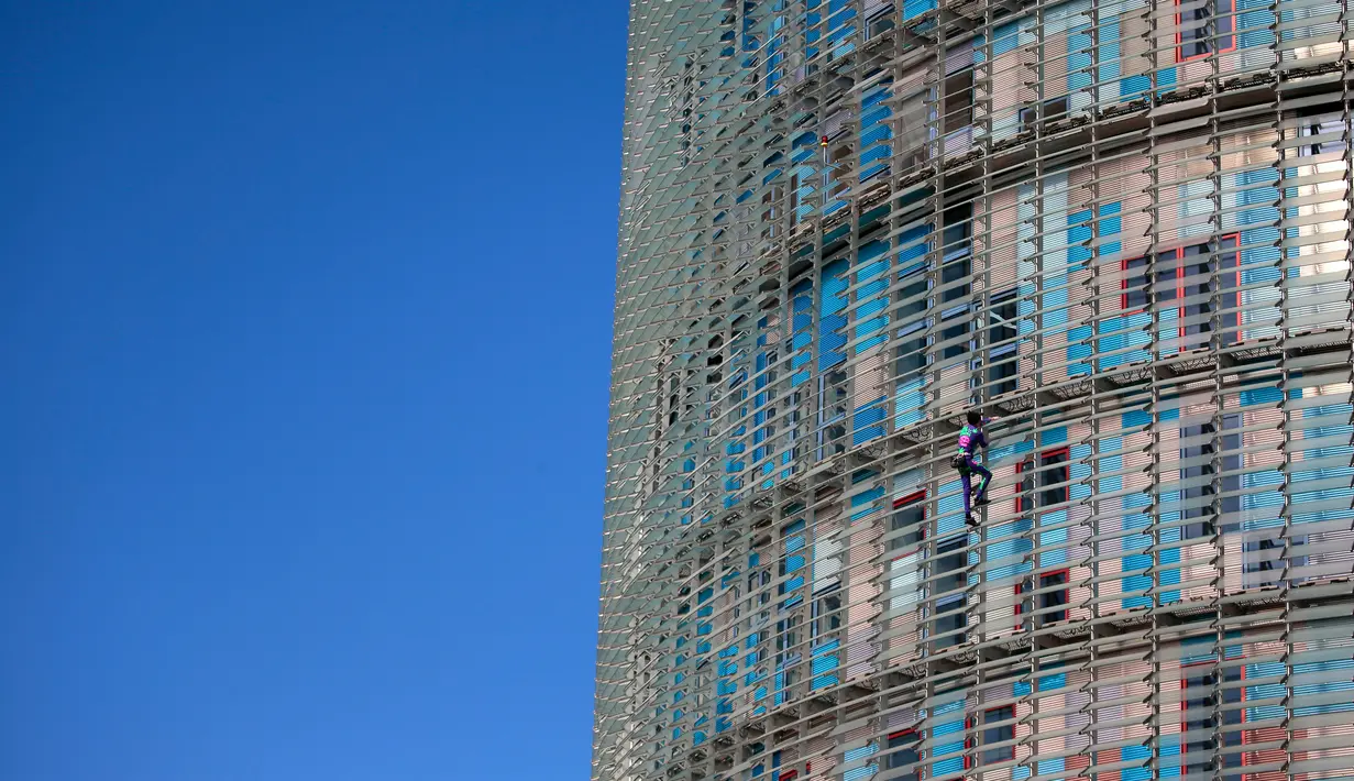 Pendaki pencakar langit, Alain Robert, yang juga dikenal sebagai 'Spiderman Prancis' memanjat Menara Agbar setinggi 144 meter di Barcelona, Rabu (4/3/2020). Aksi itu untuk menyerukan pemerintah dan individu di dunia agar lebih bertanggung jawab dalam menghadapi virus corona COVID-19. (AP/Joan Mateu)