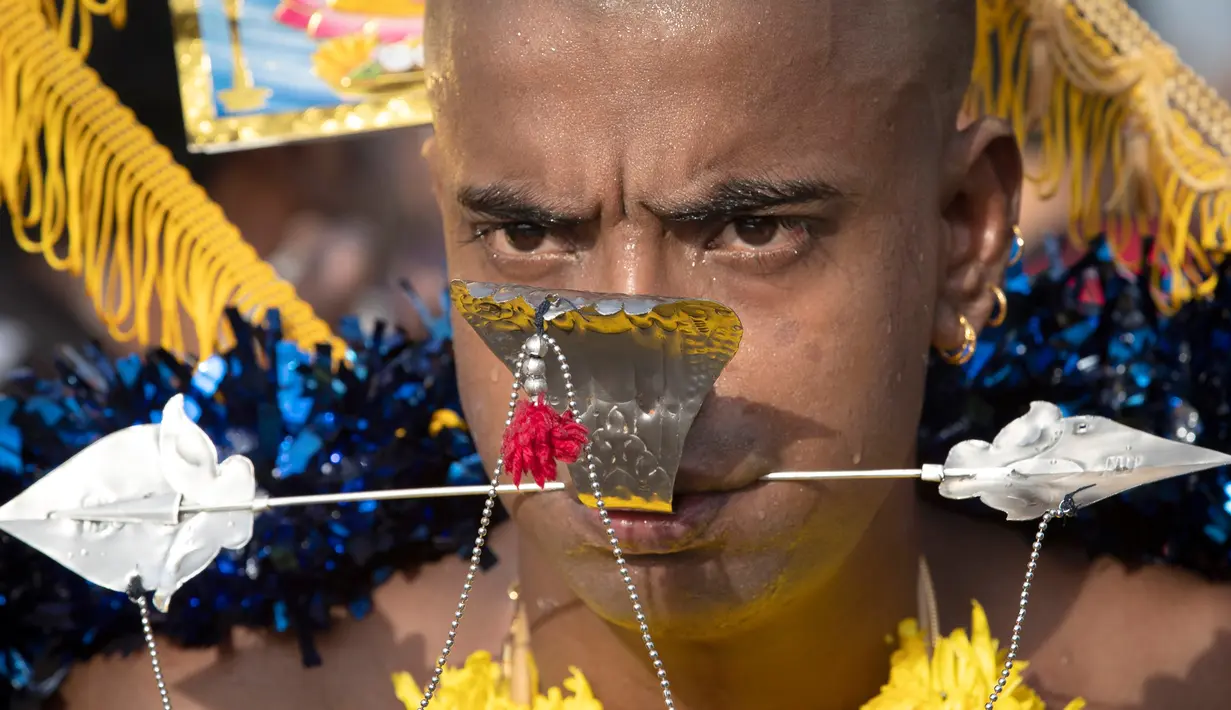 Seorang pria menusuk pipinya dengan batang logam saat Festival Thaipusam di Gua Batu, Kuala Lumpur, Malaysia, Senin (21/1). Prosesi tahunan ini dirayakan oleh umat Hindu di seluruh dunia untuk menghormati Dewa Murugan. (AP Photo/ Vincent Thian)