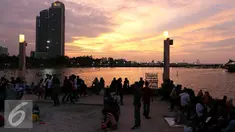Warga Jakarta menikmati matahari terbenam di akhir 2016 di Ancol, Jakarta, Sabtu (31/12). Sebagian masyarakat merayakan pergantian tahun baru di pesisir Jakarta untuk menikmati matahari terbenam. (Liputan6.com/Angga Yuniar)