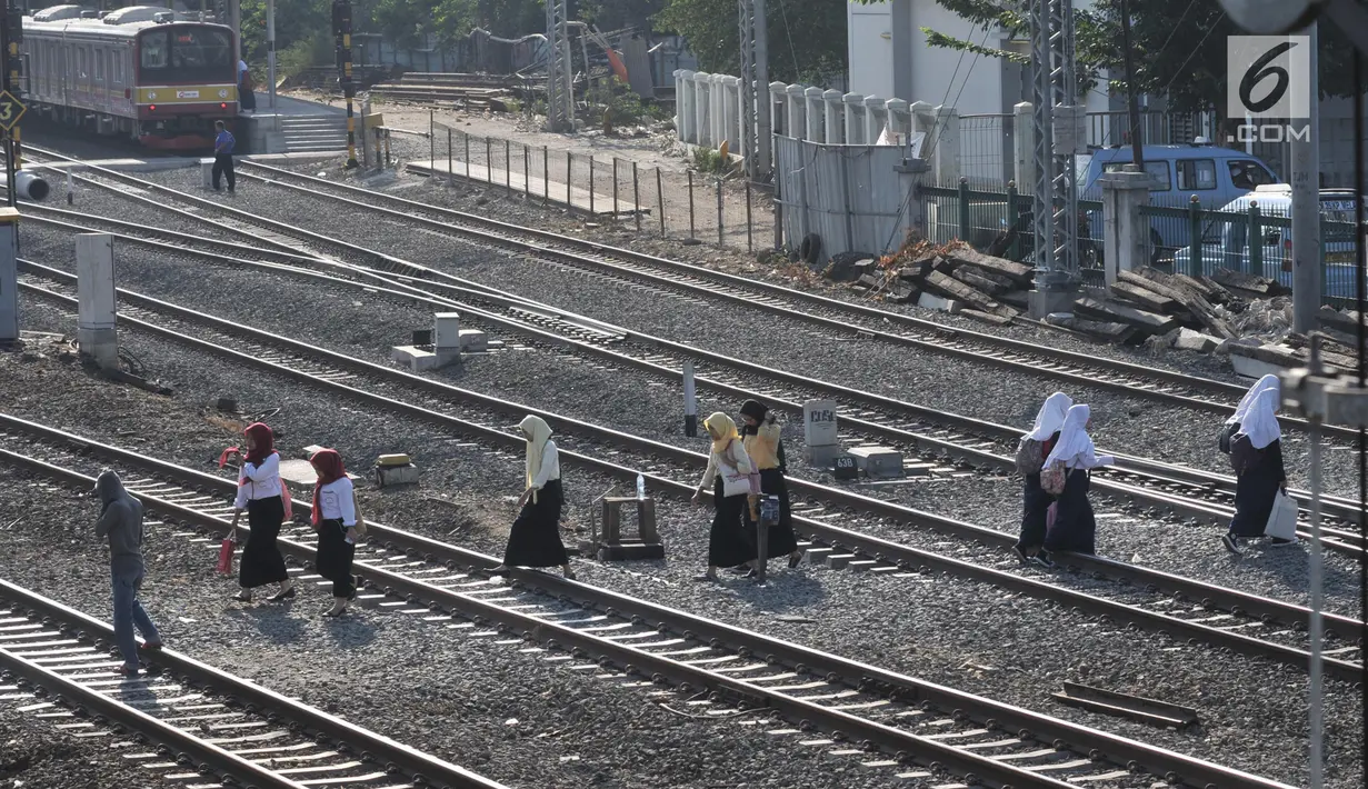 Sejumlah pelajar menyeberangi perlintasan rel kereta api di kawasan Pisangan Baru, Jakarta, Selasa (10/9/2019). Mereka nekat menantang maut menyeberangi rel di dekat stasiun Jatinegara tersebut lantaran tidak adanya akses jembatan penyeberangan orang (JPO). (merdeka.com/Iqbal Nugroho)