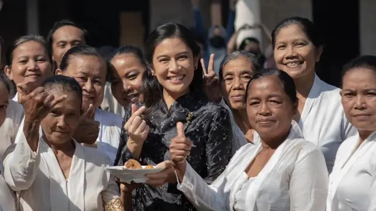 Dian Sastro mempesona dengan kebaya hitam klasiknya, berpose di antara ibu-ibu, menciptakan kesan kemewahan yang tak terbantahkan.