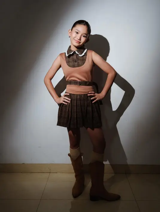 Bilqis terlihat lebih playful dengan sleeveless dress berkerah tartan cokelat gelap. Dipadu dengan outer u-neck, ikat pinggan, dan boots suede [@ayutingting92]