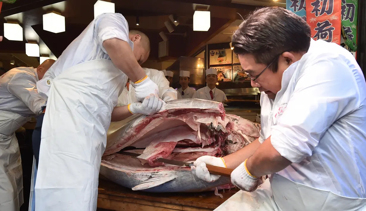Pekerja jaringan restoran sushi ternama Sushizanmai mengiris tuna sirip biru seberat 276 kg yang dibeli perusahaannya di restoran utama mereka di Tokyo, Minggu (5/1/2020). Tuna raksasa itu dibeli dalam lelang perdana 2020 dengan harga USD 1,8 juta atau sekitar Rp 24 miliar. (Kazuhiro NOGI / AFP)