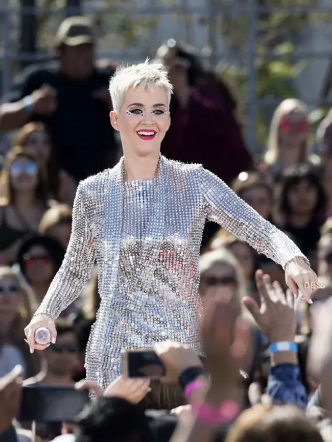 Penampilan Katy saat itu kabarnya sangat mempesona. Ia memakai dress berwarna nude dengan aksesoris kalung serta kaca mata dan anting penuh warna yang menghiasi telinganya. (AFP/VALERIE MACON)