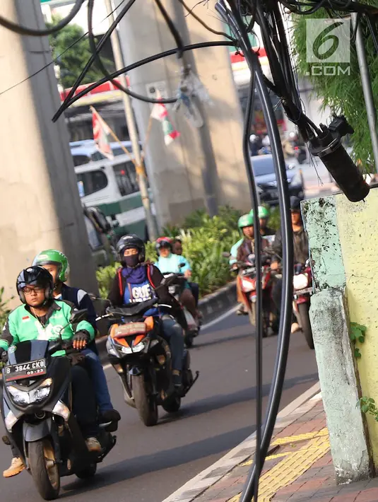 Instalasi kabel menjuntai ke trotoar di Jalan Kyai Maja, Jakarta, Rabu (10/4). Selain menganggu kenyamanan pejalan kaki, kondisi instalasi kabel yang semrawut tersebut juga berbahaya apabila mengandung aliran listrik. (Liputan6.com/Immanuel Antonius)