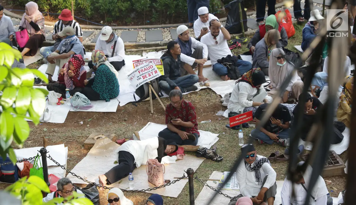 Massa aksi duduk-duduk beristirahat di taman belakang patung kuda Arjuna Wiwaha di Jalan Medan Merdeka Barat, Jakarta, Kamis (27/6/2019). Massa aksi berkumpul terkait pelaksanaan sidang putusan perselisihan hasil Pilpres 2019 di Gedung Mahkamah Konstitusi. (Liputan6.com/Helmi Fithriansyah)